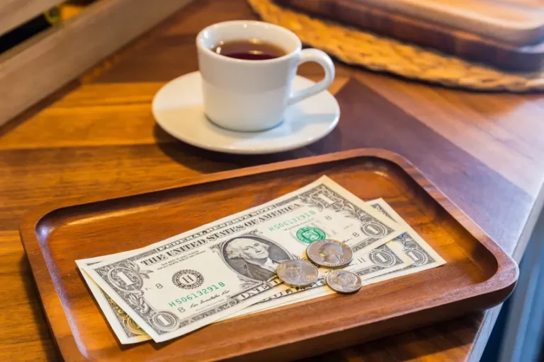cup of coffee on a table with a cash tip beside it