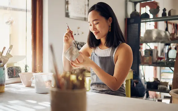 Business owner painting in her pottery studio