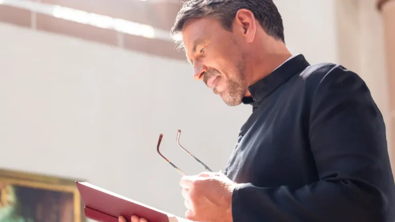 Catholic priest holding a Bible.