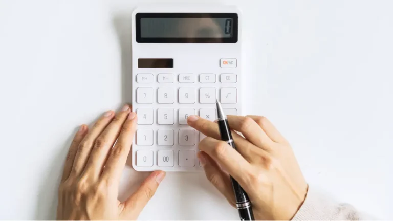 Business owner using a white calculator to determine profitability.