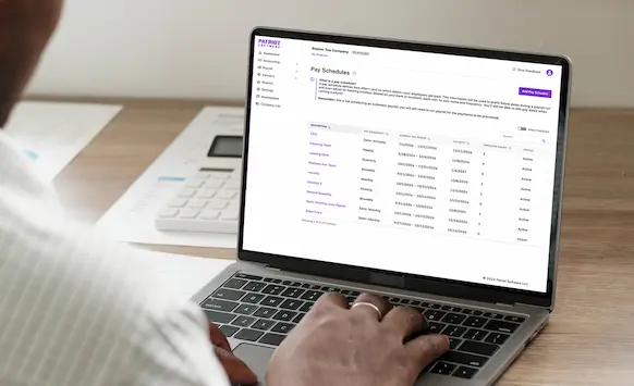 Person using laptop to review pay schedules they set up in Patriot Payroll