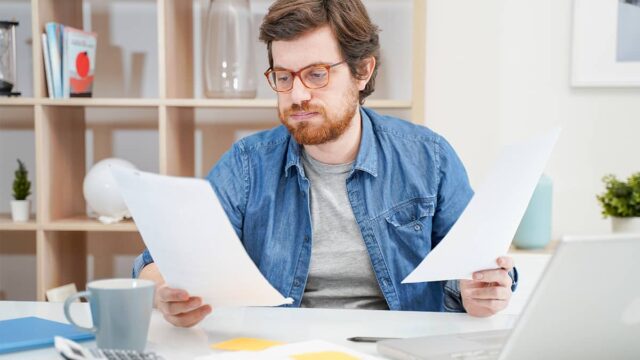 man deciding how to calculate a raise by looking at papers